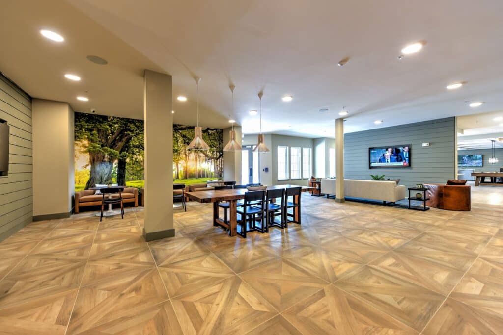 Spacious modern lobby with wooden flooring, seating areas, and large wall murals depicting nature.