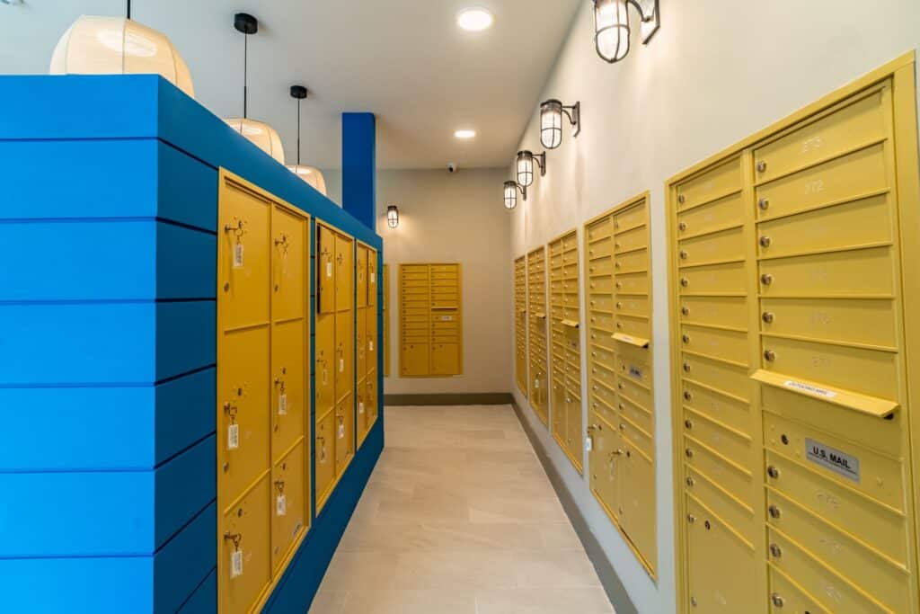 A hallway with blue and yellow mail lockers, illuminated by ceiling lights.